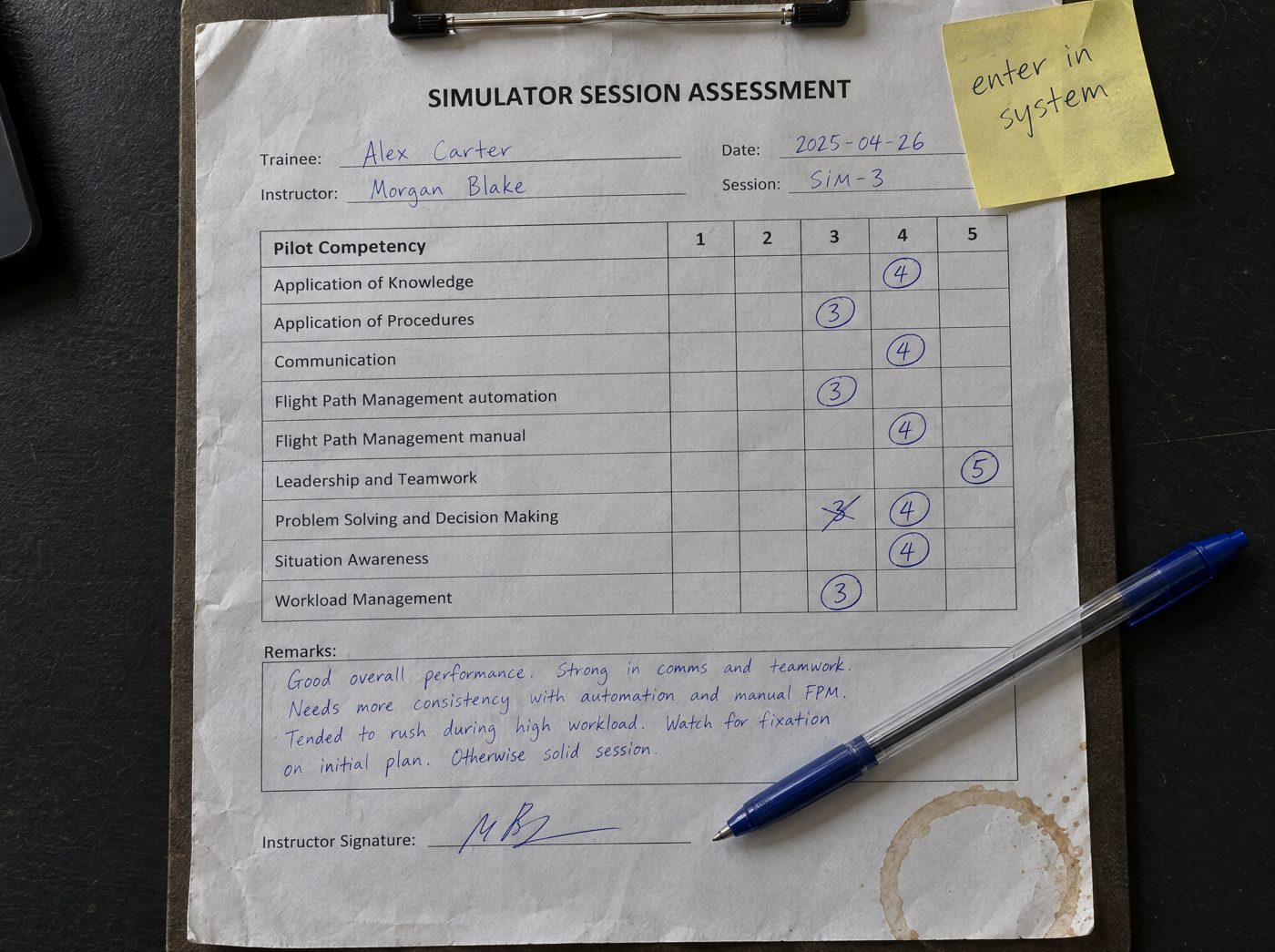 A paper simulator assessment form on a clipboard, grades circled by hand, a coffee ring and a sticky note saying enter in system